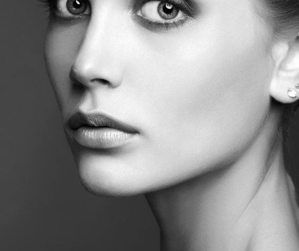 Black and white portrait of a woman with visible tear trough hollowing and mild under-eye shadowing, showing smooth skin texture and defined facial contours.