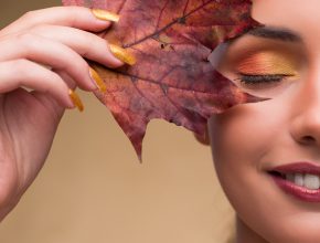 Smiling woman posing with autumn leaf
