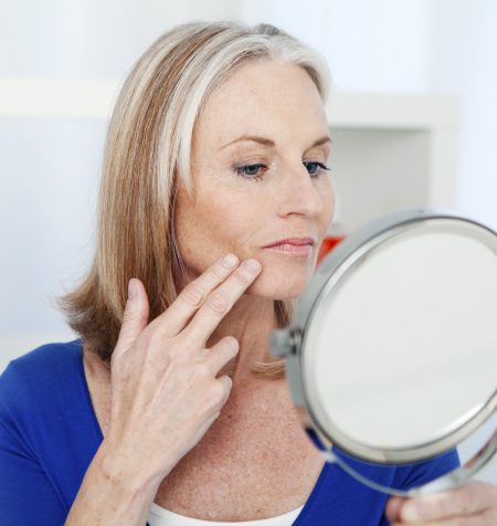 Woman examining marionette lines in mirror