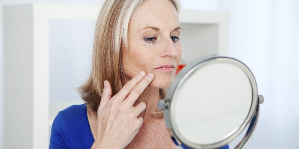 Woman examining marionette lines in mirror