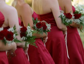 bride mates in the red dresses with red roses in hands