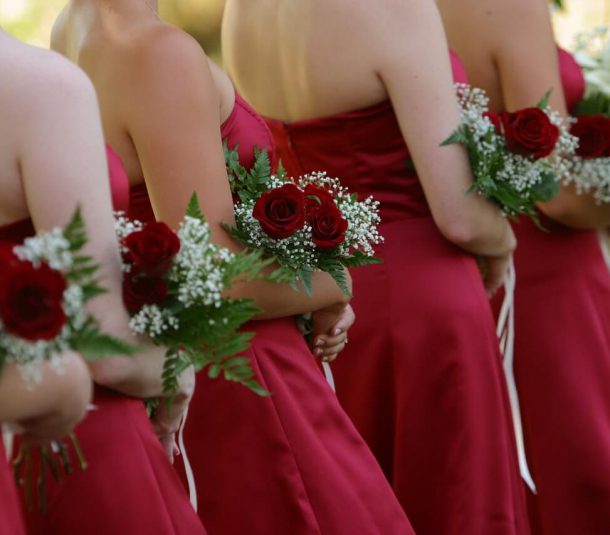 bride mates in the red dresses with red roses in hands